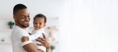 Çocuk Bakımı. Gülümseyen Siyahi Baba 'nın, yeni doğmuş bebeği kucağında tutarken evinin penceresinde poz verirken, Afrikalı Baba' nın şirin çocuk ile bağ kurması, Kopya Alanlı Panorama