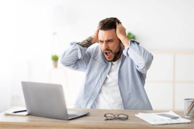 Yazılım, web sitesi hatası, dizüstü bilgisayara bakmak ve el kol hareketi, ev içi iş yerinde oturmak, boş alan. Genç adam kumar oynarken, internette oynarken kaybediyor.