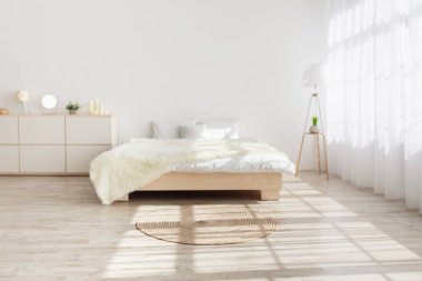 Yatak odasında modern minimalist tasarımı olan kimse yok. Yastıklı ve battaniyeli çift kişilik yatak, mobilya, lamba, yerde halı, büyük perdeli pencere, beyaz arka plan, kopyalama alanı, bulanık