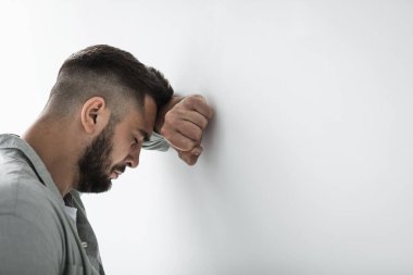 Sorun ve sorun hakkında düşünmek, depresyon ya da yalnızlık, akıl hastalığı gibi zor kararlar verir. Üzgün, genç, çekici, sakallı erkek, gri duvarda dinleniyor ve ağlıyor.