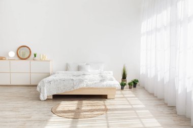 Eko minimal modern İskandinav ev tarzı. Yatak, ahşap zemin üzerinde sabah ışığı perdeleri, masası, bitkileri, mobilyaları, beyaz arka planda yatak odasının iç tarafında, boş alan