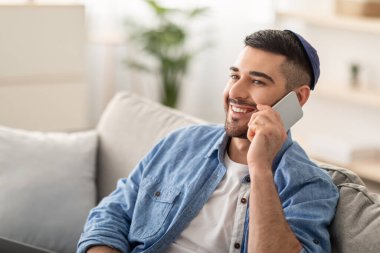 Kipa 'da cep telefonuyla konuşan yakışıklı Yahudi' nin yakın plan portresi, içeride taksi ya da yemek siparişi veren. Gülümseyen genç işadamı ortakları ya da müşterileri arıyor.