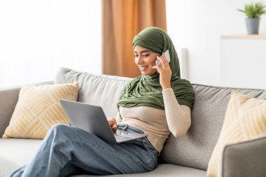 Türbanlı genç bir Arap kadın evinden uzak bir iş görüşmesi yapıyor. Bilgisayarını ve akıllı telefonunu kullanıyor, çalışırken pozitif bir tavır sergiliyor..