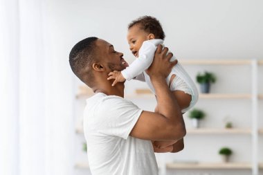 Babalar Günü Konsepti. Siyah babayı sevmek, tatlı bir bebeğin içinde yükselmek, Afrikalı Amerikalı babayla ilgilenmek, sevimli küçük çocukla evde vakit geçirmek, birlikte vakit geçirmek, uzay kopyalamak...