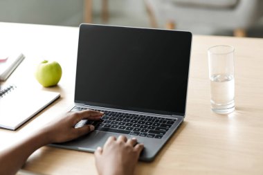 Genç Afro-Amerikan kız okulunun dizüstü bilgisayarında boş ekranla yazı yazması ve iç kısımda okuması, kırpıldı. Covid-19 salgını, yeni normal ve modern ders uzaktan, öğrenci ev ödevi yapıyor, pov