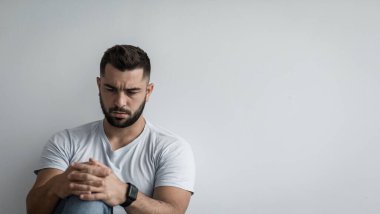Negatif insani duygular, derin depresyon, yalnızlık, üzüntü, stres ve psikolojik sorunlar. Ciddi yakışıklı, kaslı, sakallı adam kaygılı, gri duvarlı arka planda, kopyalama alanı