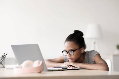 Cihazlı ev eğitimi, online öğrenim ve ders, öğrenci ve bilgi. Gözlüklü, yorgun, Afro-Amerikan kız oturma odasında dizüstü bilgisayarla video izliyor.