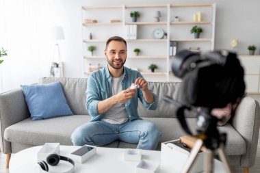 Popüler erkek blogcu, evdeki profesyonel kamerayla yeni kulaklıklar hakkında video eleştirisi çekiyor. Garip içerik yapıcı modern aygıt öneriyor, sosyal ağ için yayın yapıyor