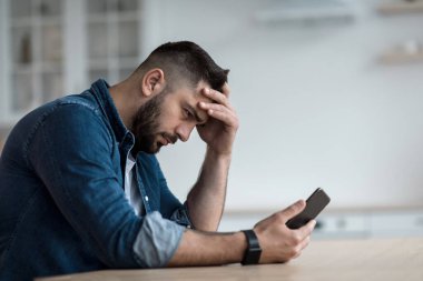 Aramayı, sorunları, zorlukları, stresi bekliyorum ama cevap yok. Mutsuz, üzgün, hayal kırıklığına uğramış sakallı genç adam akıllı telefona bakıyor ve kafa kafaya verip mutfak masasında oturuyor.