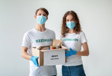İki milenyum yılı gıda bağışları bir kutu dolusu ürün ve konserve mal barındırıyor. Bir yardım merkezinde insani yardım sıralarken tıbbi maske ve mavi eldiven takıyorlar..