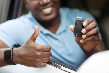 Tanımlanamayan siyah adam otomatik araba anahtarı ve baş parmağını gösteriyor. Otomobil kiralayan ya da alan, oto kuaför ya da kiralama hizmeti veren Afrikalı Amerikalı sürücüler.