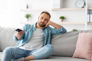 Evdeki kanepede televizyon seyreden, uzaktan kumandalı, sıkılmış genç bir adam. Bin yıllık beyaz adam televizyonda kanal değiştiriyor, film ya da programla ilgilenmiyor.