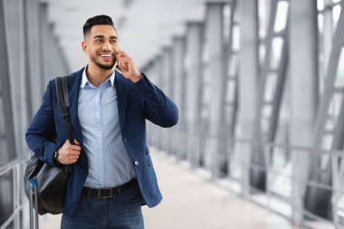 Havaalanında sırt çantasıyla gezerken cep telefonuyla konuşan yakışıklı Arap adam, genç orta doğulu iş adamı yurtdışında mobil iletişim için gezinme hizmetinin keyfini çıkarıyor, uzayı kopyalıyor