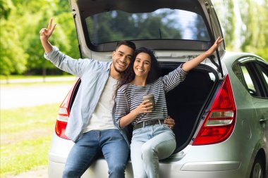 Mutlu aşıklar kameraya sarılıp gülümserken kahve içip el kaldırıyorlar. Neşeli orta doğu çifti araba yolculuğunun tadını çıkarıyor, bagajda dinleniyorlar.