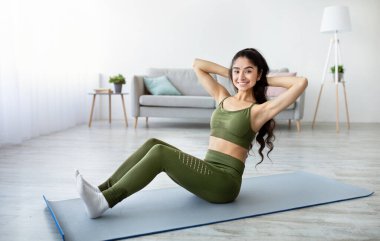 Atletik Hintli kadın yoga minderi üzerinde egzersiz yapıyor, evde karın kaslarını güçlendiriyor. Çekici Doğulu kadın formda ve sağlıklıymış. Yurtiçi spor konsepti