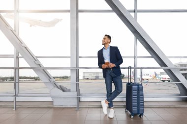 Havalimanı Terminali 'nde, yanında bavul taşıyan yakışıklı Arap Pasaportu ve Biletleri Bekleyen Genç Orta Doğulu Girişimci, Keyifli İş Gezisi, Kopya Alanı