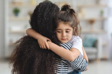 Üzgün küçük bir kız annesine sarılıyor, ev içi, yakın plan portre, fotokopi odası. Uzun saçlı, orta doğulu bir anne, üzgün, ağlayan kızını teselli ediyor. Annelik, anne sevgisi kavramı