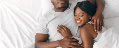 Bir erkek ve kadın yatakta birlikte uzanır, gülümser ve birbirlerine sarılırlar. Rahat ve mutlu görünüyorlar. Rahat bir ortamda. Parlak sabah ışığı içeri süzülüyor..