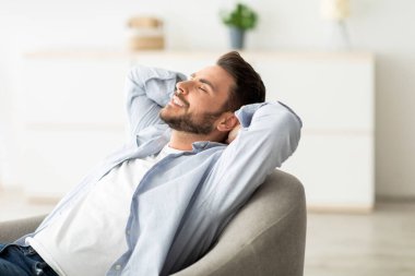 Tembel bir gün. Mutlu, rahat bir adam rahat koltukta dinleniyor, el ele tutuşuyor, gözleri kapalı oturuyor ve minimalizm yaşam tarzının ve konforunun tadını çıkarıyor.