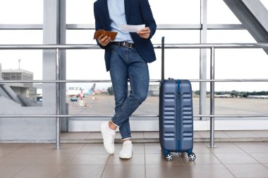 Havaalanı Terminali 'nin yanında bavul başında dururken biletlerdeki uçuş süresini kontrol eden tanınmayan adam, erkek yolcu uçuşu için bekliyor, gezintiye hazır, kesilmiş resim, boş alan