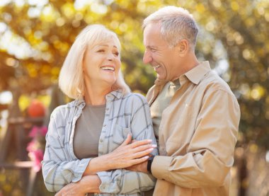 Romantik son sınıf çifti parkta aşk anının tadını çıkarıyor, güneşli bir sonbahar gününde yürüyor ve birlikte vakit geçiriyorlar, birbirlerine bakıp gülümsüyorlar.