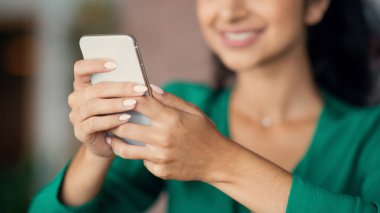 Tanımlanamayan genç bir kadın, kafede öğle yemeği molası veriyor, masada tek başına oturuyor, modern akıllı telefon kullanıyor, sosyal medyayı kontrol ediyor ya da kopyalanmış, panorama yapan biriyle sohbet ediyor.