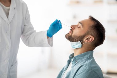 Coronavirus test prosedürü. Doktor, evdeki çubukla milenyum çocuğu için nazal PCR testi yapıyor. Genç beyaz adam koronavirüs teşhisi yapıyor. Sağlık hizmeti kavramı