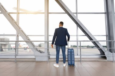 Uçuşu bekliyorum. Havaalanı Terminali 'nin yanında duran valizli adam, tanınmayan erkek yolcu uçaktan inmeye hazır, seyahate ya da iş seyahatine hazır,