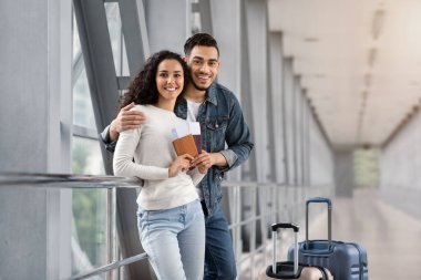 Tatil gezisi. Mutlu Arap Eşler Havalimanı Terminalinde poz veriyor, neşeli Orta Doğu gezginleri uçuşu bekliyor, kameraya bakıyor, gülümsüyor, birlikte seyahat ediyor,