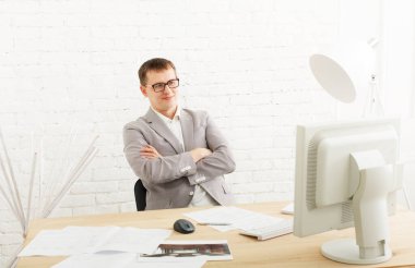 Gülümseyerek, bilgisayar masada oturan beyaz modern ofis iç çalışma genç iş adamı. Ofis çalışanı göz gözlük, erkek, iş İnternet. Yüksek anahtar, yumuşak sesi. Modern ofis iş adamı.