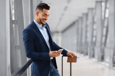 İnternetten Hotel Rezervasyon. Genç Arap İşadamı Havalimanında Beklerken Akıllı Telefon Kullanıyor, Orta Doğulu Takım Elbiseli Adam Yurtdışına Seyahatten Önce İnternet 'te Konaklama Yapıyor, Boşluğu Kopyala