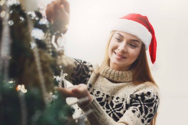 Noel ağacı süsleme santa şapka genç güzel kadın. Şık modern tasarım, altın baubles, beyaz boncuk ve parlak garland. Kış tatil arka plan kopya alanı ile