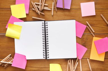 Şeyler unutma. Kırtasiye malzemeleri, üstten görünüm düz ahşap Ofis Masası açık not defteri, kalem ve birçok renkli boş bellek sopa ve faturası notlar, ile atış yatıyordu kimse kopya alanı, şablon