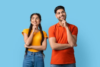 İki genç yetişkin, parlak mavi bir arkaplanda yan yana durur, her ikisi de gülümserler. Neşeli bir sohbete dalarlar ve birlikte bir şeyler düşünüyor gibi görünürler..