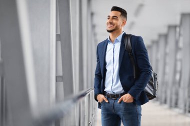 Yolculuk için hazır. Sırt çantalı yakışıklı bir Arap, havaalanı terminalinde dikiliyor ve pencereye bakıyor, gülümseyen bir Orta Doğulu adam uçuşu bekliyor, hava yolculuklarının keyfini çıkarıyor, boşluğu kopyalıyor.