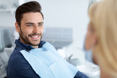 Rahatlamış yakışıklı adam dişçisine gülümsüyor, yandan bakıyor, fotokopi çekiyor. Barışçıl sakallı adam doktor stomatoloğuyla konuşuyor, yeni diş kliniğinde modern tedavinin tadını çıkarıyor.