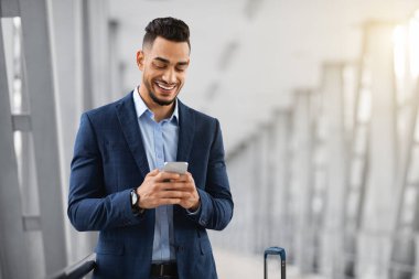 Mobil İletişim. Havalimanı Terminalinde beklerken akıllı telefon kullanan yakışıklı Middel İşadamı, Arkadaşlarıyla Neşeli Arap Mesajlaşan ya da İnternet Tarayıcı, Uzay Kopyalama