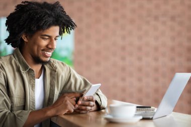 İyi ki siyah kıvırcık çocuk akıllı telefondan yazı yazıyor. Laptop, defter ve kahveyle aynı masada oturuyor. Kafenin içinde boş yer var. Çalışma ve uzaktan çalışma, bağımsız müteahhit, serbest ve yeni uygulama