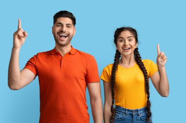 İki arkadaş bir arada durarak sevinç ve heyecan ifade eder. İkisi de yukarıyı gösteriyor, geniş bir kesime gülümsüyor, canlı bir ortamda eğlenceli ve pozitif bir atmosfer sergiliyorlar..