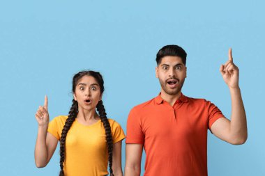 Kırmızı gömlekli genç bir adam ve sarı gömlekli genç bir kadın yan yana durdular. İkisi de şaşırmış ve ellerini kaldırdılar. Heyecanlı ve meraklı görünüyorlar..