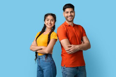 Genç bir adam ve kadın sırt sırta dururlar, mavi bir arka planda parlak bir şekilde gülümserler. Rahat pozları ve neşeli ifadeleri güçlü bir dostluk ya da bağ olduğunu gösteriyor..