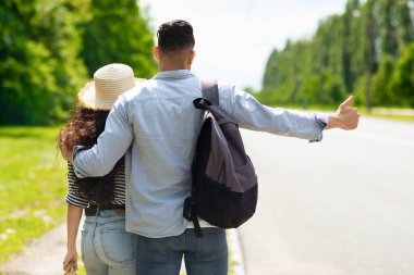 Bir çiftin otostop çekişini, baş parmağıyla arabayı durduruşunu. Sırt çantalı genç, tanınmayan kıvırcık kadın ve erkek. Birlikte geziyorlar. Couyntryside 'da yürüyüş yapıyorlar.