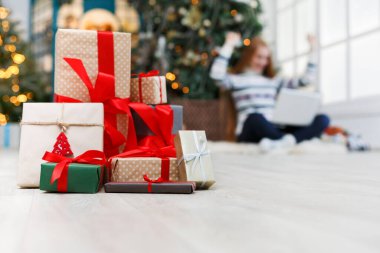 Kış tatil arka plan. Noel hediye kutuları bant ile dekore edilmiş xmas ağacı ve mutlu genç kız zemin kırmızı kurdele portre. Seçici odak, kopya alanı