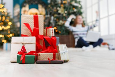 Kış tatil arka plan. Noel hediye kutuları bant ile dekore edilmiş xmas ağacı ve mutlu genç kız zemin kırmızı kurdele portre. Seçici odak, kopya alanı