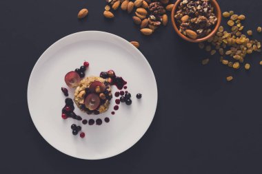 Sağlıklı Kahvaltı, diyet ve detoks kavramı - kepekli taze yulaf lapası meyve, çilek ve bej renkli arka plan üzerinde fındık ile plaka üzerinde. Natürmort, üstten görünüm