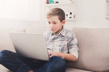 Child and internet, engrossed boy with laptop at home