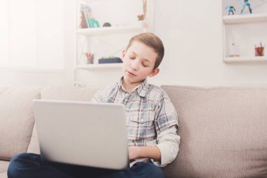 Bilgisayar kanepede evde sıkılmış çocuk. Klavyede yazarak internette ilginç içerik bulmaya çocuk