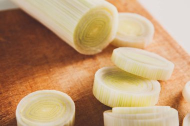 Sağlıklı yemekler pişirmek. Dilimlenmiş ve doğranmış pırasa closeup ahşap arka plan üzerinde