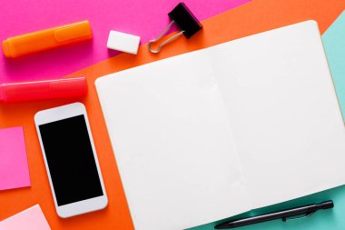 Parlak ve renkli bir çalışma alanı çok renkli bir yüzey üzerinde duran boş bir defter içerir..