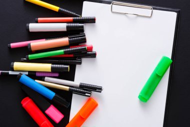 Bir not panosundaki boş bir not defterinin etrafına çeşitli renkli işaretler saçılmış. Bu ayar çizim ve yazma yoluyla yaratıcılığı teşvik ediyor, sanatsal bir çalışma alanı için mükemmel..